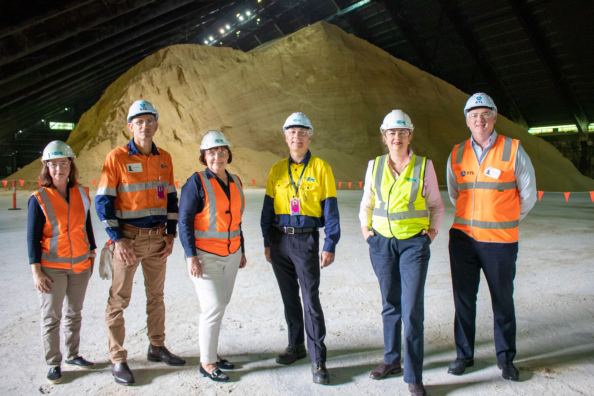 People standing in front of 85,000 tonnes of sugar ready to be shipped from the Port of Mackay.